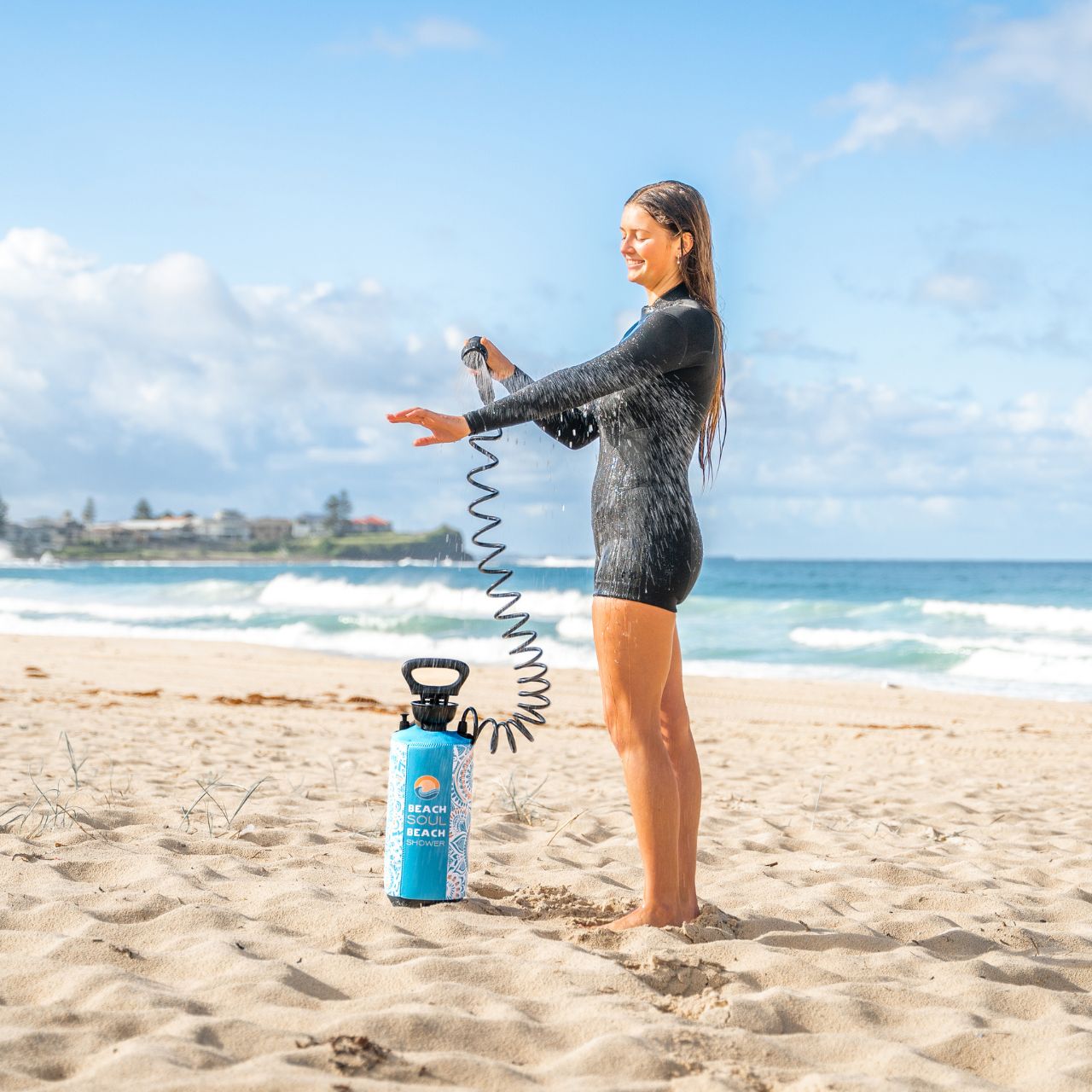 Woman using the Bliss Out portable shower to rinse off after the beach