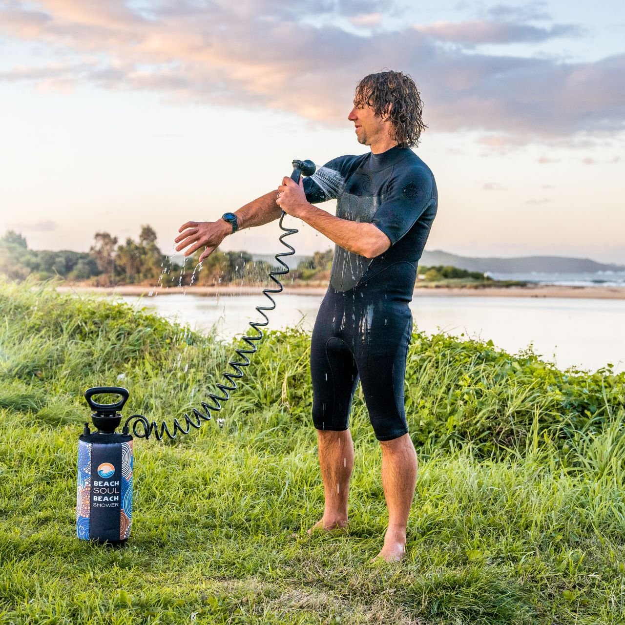 Woman using the Jamigam portable shower in a grassy outdoor setting