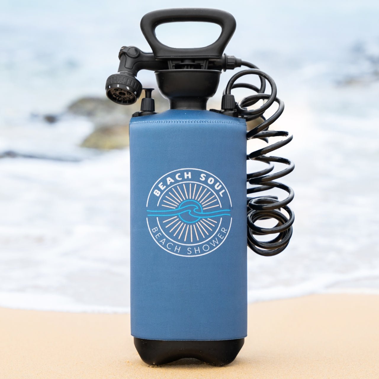 Ocean Rise 8L portable shower with coiled hose and shower head at the beach