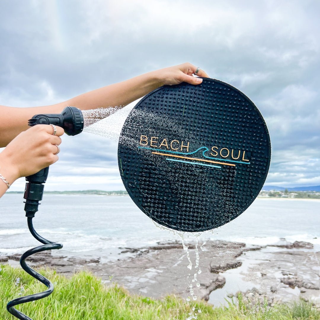 Beach Soul outdoor shower mat being rinsed clean with a Beach Soul portable shower
